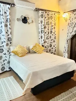 a bedroom with a bed with yellow pillows and curtains at Little Africa in Midrand in Randjesfontein