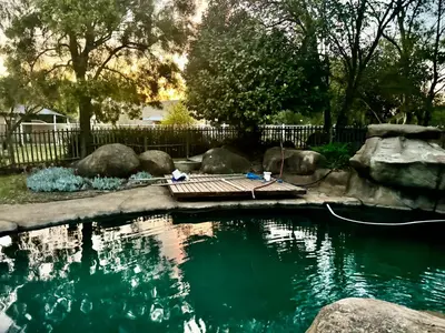 a pool of water with rocks and a fence at Little Africa in Midrand in Randjesfontein