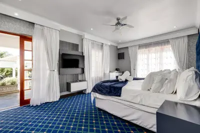 a bedroom with a large bed and a television at The Diplomat in Midrand