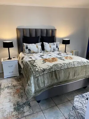 a bedroom with a large bed with two lamps on tables at Cozy Garden Flat with Garden in Pretoria