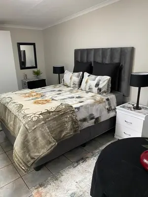 a bedroom with a large bed and two lamps at Cozy Garden Flat with Garden in Pretoria