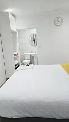 a bedroom with a white bed and a toilet at HMT Exquisite Spaces in Polokwane