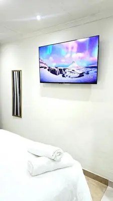 a flat screen tv hanging on a wall in a bedroom at HMT Exquisite Spaces in Polokwane