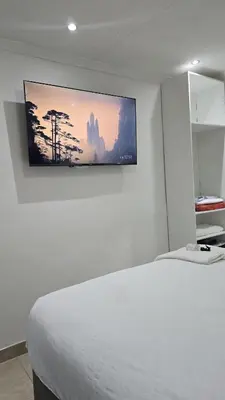 a bedroom with a bed with a tv on the wall at HMT Exquisite Spaces in Polokwane