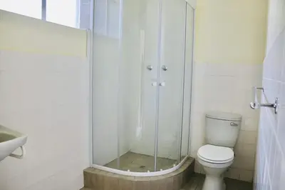 a bathroom with a shower and a toilet and a sink at Heideland in Pretoria