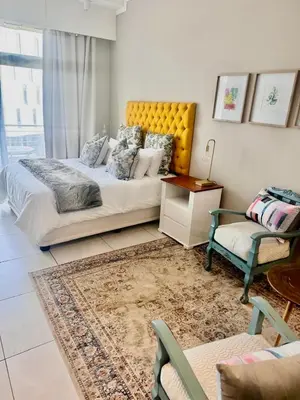 a bedroom with a bed and a couch and a chair at Menlyn Main Apartments Trilogy in Pretoria