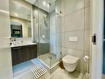 a bathroom with a shower and a toilet and a sink at Menlyn Main Apartments Trilogy in Pretoria