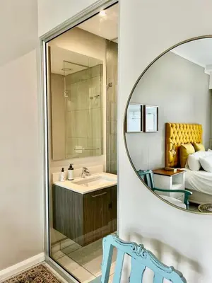 a bathroom with a mirror and a sink and a bed at Menlyn Main Apartments Trilogy in Pretoria