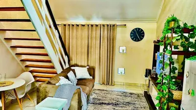 a living room with a couch and a clock on the wall at Loft On Grosvenor in Pretoria