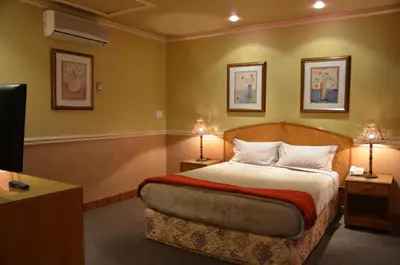 a bedroom with a bed with two lamps and a tv at The Lodge Bethal in Bethal