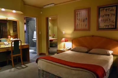 a bedroom with a bed and a desk and a bathroom at The Lodge Bethal in Bethal