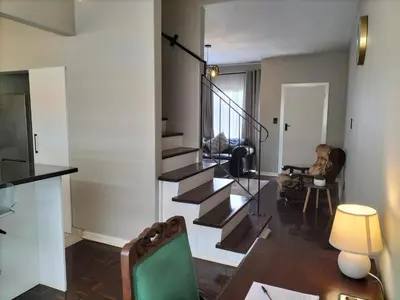 a living room with a staircase and a person sitting in a chair at Rhodesfield's Hidden Gem in Kempton Park