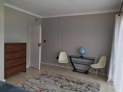 a bedroom with two chairs and a dresser and a bed at Rhodesfield's Hidden Gem in Kempton Park