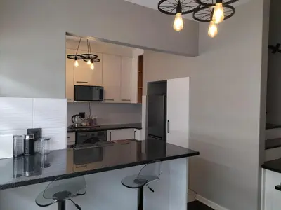a kitchen with white cabinets and a black counter top at Rhodesfield's Hidden Gem in Kempton Park