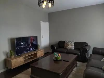 a living room with a couch and a tv at Rhodesfield's Hidden Gem in Kempton Park