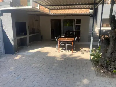 a patio with a wooden table and chairs in front of a house at The Hideaway in Nelspruit