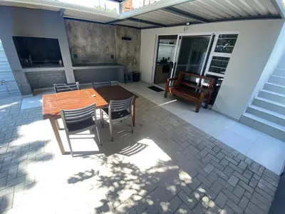a patio with a wooden table and chairs and a bench at The Hideaway in Nelspruit