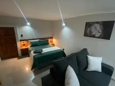 a living room with a couch and a bed at The Hideaway in Nelspruit
