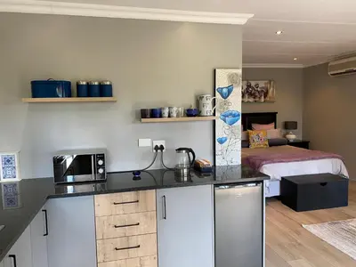 a kitchen with a bed and a kitchen counter with a microwave at Baobab Guesthouse in Centurion