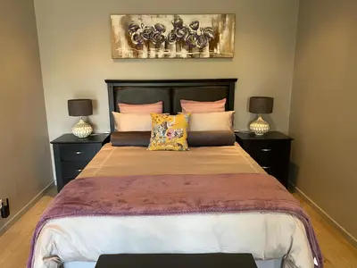 a bedroom with a large bed with two lamps at Baobab Guesthouse in Centurion