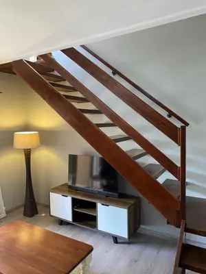 a living room with a staircase with a tv and a table at Baobab Guesthouse in Centurion