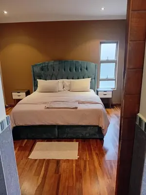 a bedroom with a large bed with a green headboard at Gillian Place in Sandton