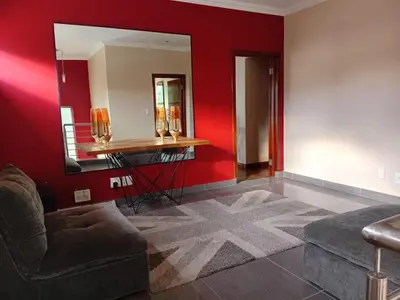 a living room with a couch and a mirror at Gillian Place in Sandton