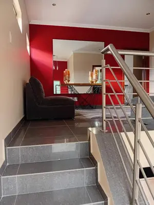 a living room with red walls and a black couch at Gillian Place in Sandton