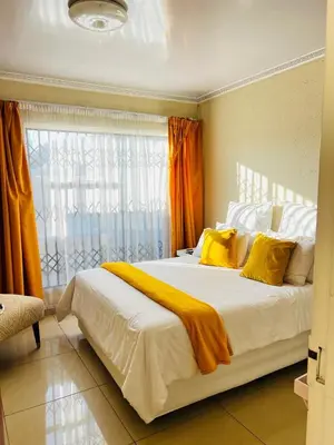 a bedroom with a large white bed with yellow pillows at The Barberton Nest in Barberton