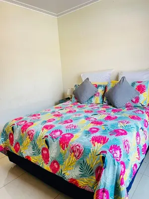 a bed with a colorful bedspread with flowers on it at The Barberton Nest in Barberton
