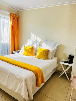 a bedroom with a large bed with yellow pillows at The Barberton Nest in Barberton