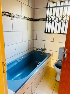 a bathroom with a blue tub and a toilet at The Barberton Nest in Barberton