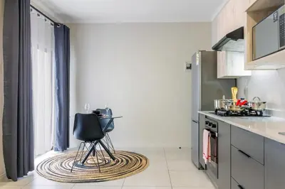 a kitchen with a black chair sitting on a rug at Ground Floor Premium Suite in Midrand