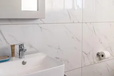 a white bathroom with a sink and a mirror at Infinite Views Penthouse in Midrand