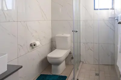 a white bathroom with a toilet and a shower at Infinite Views Penthouse in Midrand