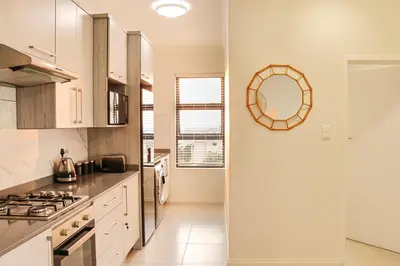 a kitchen with white cabinets and a mirror on the wall at Infinite Views Penthouse in Midrand