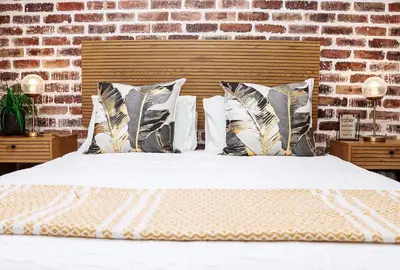 a bedroom with a white bed with pillows and a brick wall at Green Valley Apartment in Boschrand