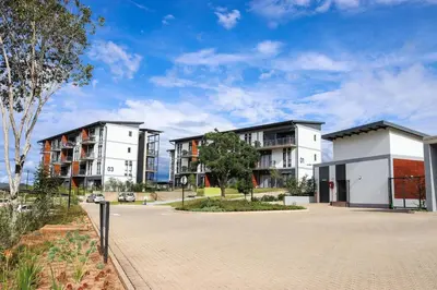 a row of apartment buildings in a parking lot at Green Valley Apartment in Boschrand