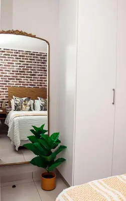 a mirror in a bedroom with a bed and a plant at Green Valley Apartment in Boschrand