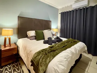 a bedroom with a large bed with green pillows at Fish Eagle Manor in Warmbaths