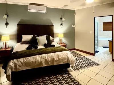 a bedroom with a large bed and a bathroom at Fish Eagle Manor in Warmbaths