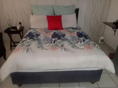 a bed with a blanket with a red pillow at Nala Guesthouse in Ellisras