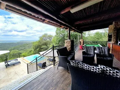 a deck with chairs and a table and a pool at Lovely family home in the bush in Warmbaths