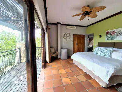 a bedroom with a bed and a balcony at Lovely family home in the bush in Warmbaths