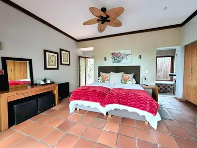 a bedroom with a large bed and a ceiling fan at Lovely family home in the bush in Warmbaths