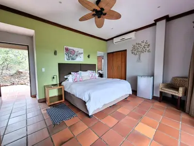 a bedroom with a bed and a ceiling fan at Lovely family home in the bush in Warmbaths