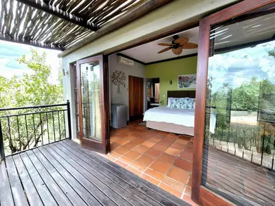 a balcony with a bedroom with a bed on it at Lovely family home in the bush in Warmbaths