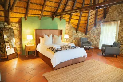 a bedroom with a bed and chairs in a room at Silverlakes Farm Hotel in Pretoria
