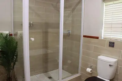 a shower stall in a bathroom with a toilet at Silverlakes Farm Hotel in Pretoria