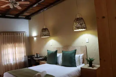 a bedroom with a bed with green pillows and two lights at Silverlakes Farm Hotel in Pretoria